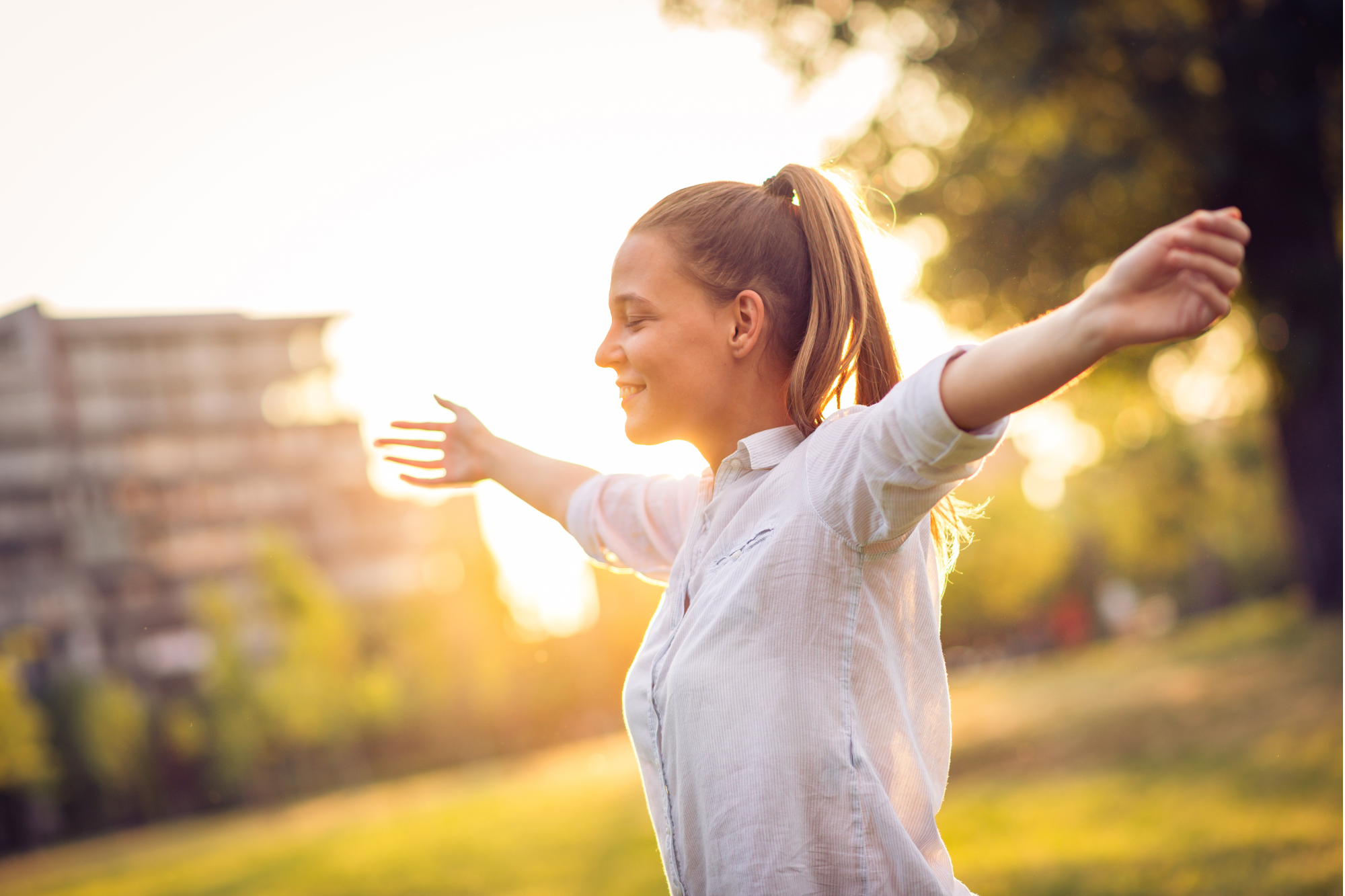 A young woman joyfully embracing the outdoors, symbolizing the empowerment and fulfillment that comes from strengths-based coaching and personal growth.