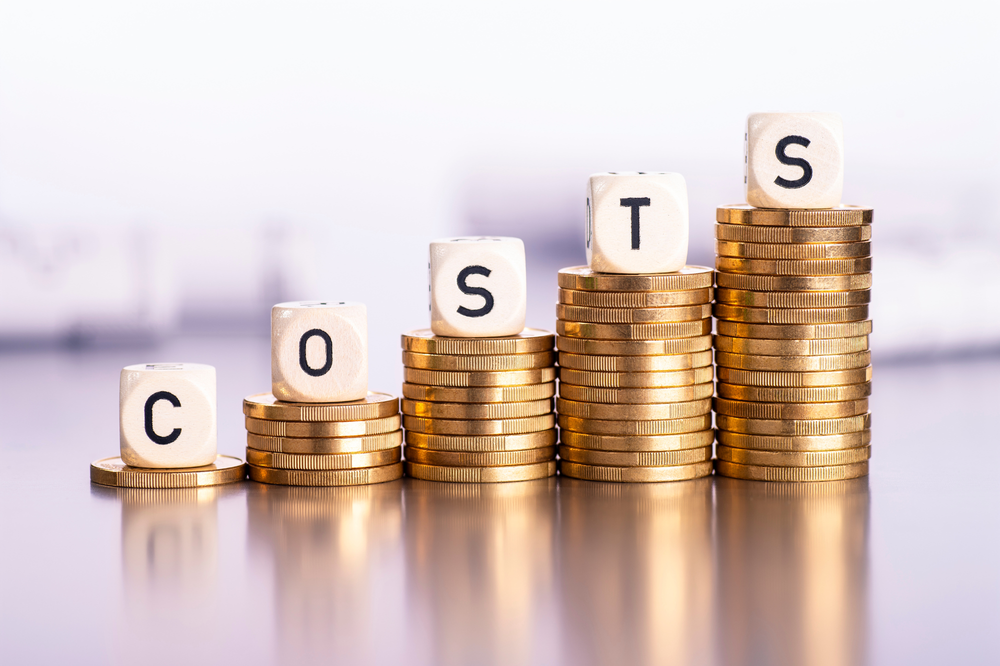 The rising cost of poor financial habits, symbolized by stacked coins with lettered blocks spelling "COSTS," highlighting how unchecked spending and financial mismanagement can accumulate over time.