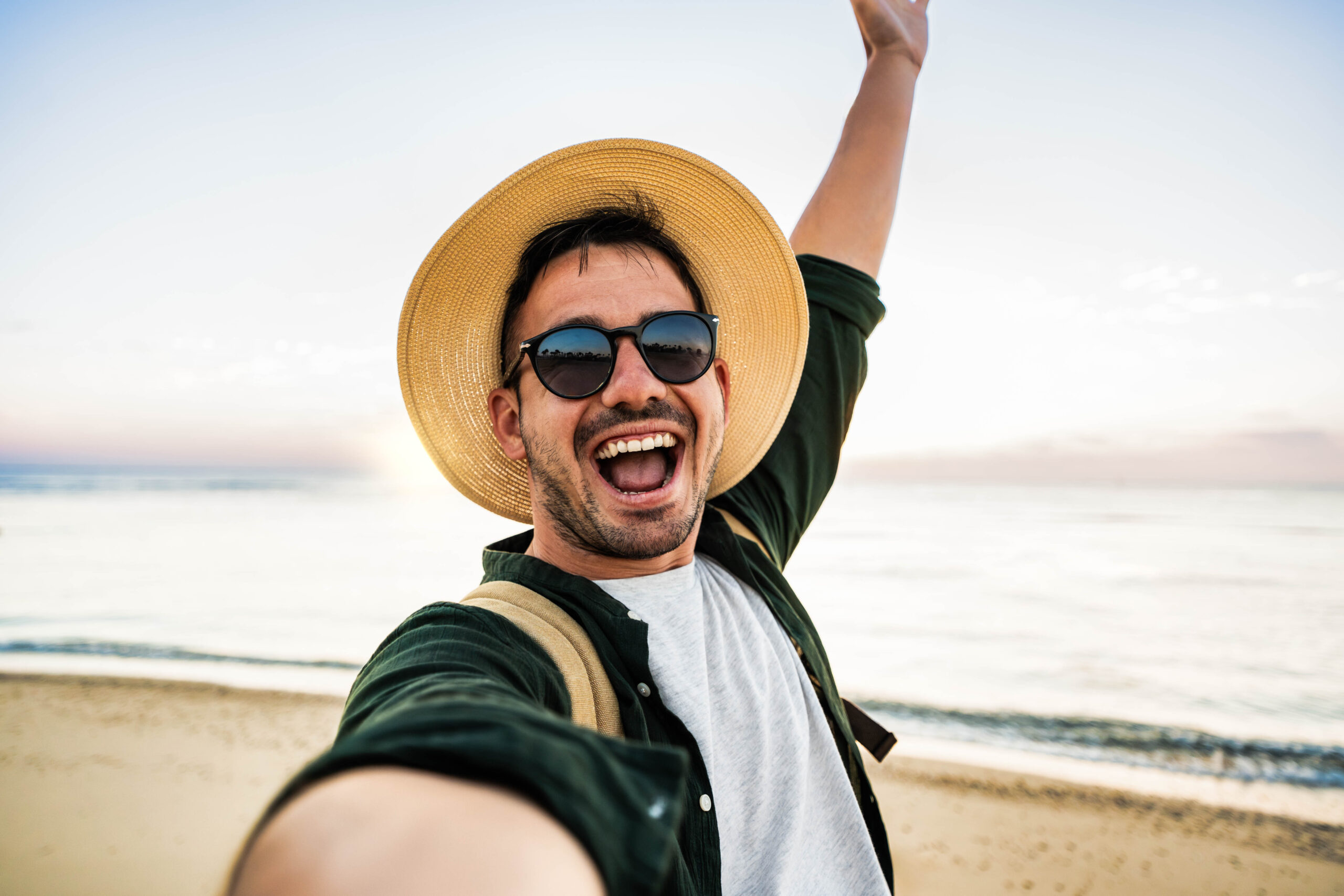 A joyful man takes a cheerful beach selfie, reflecting a fulfilled, goal-driven life through personal coaching.