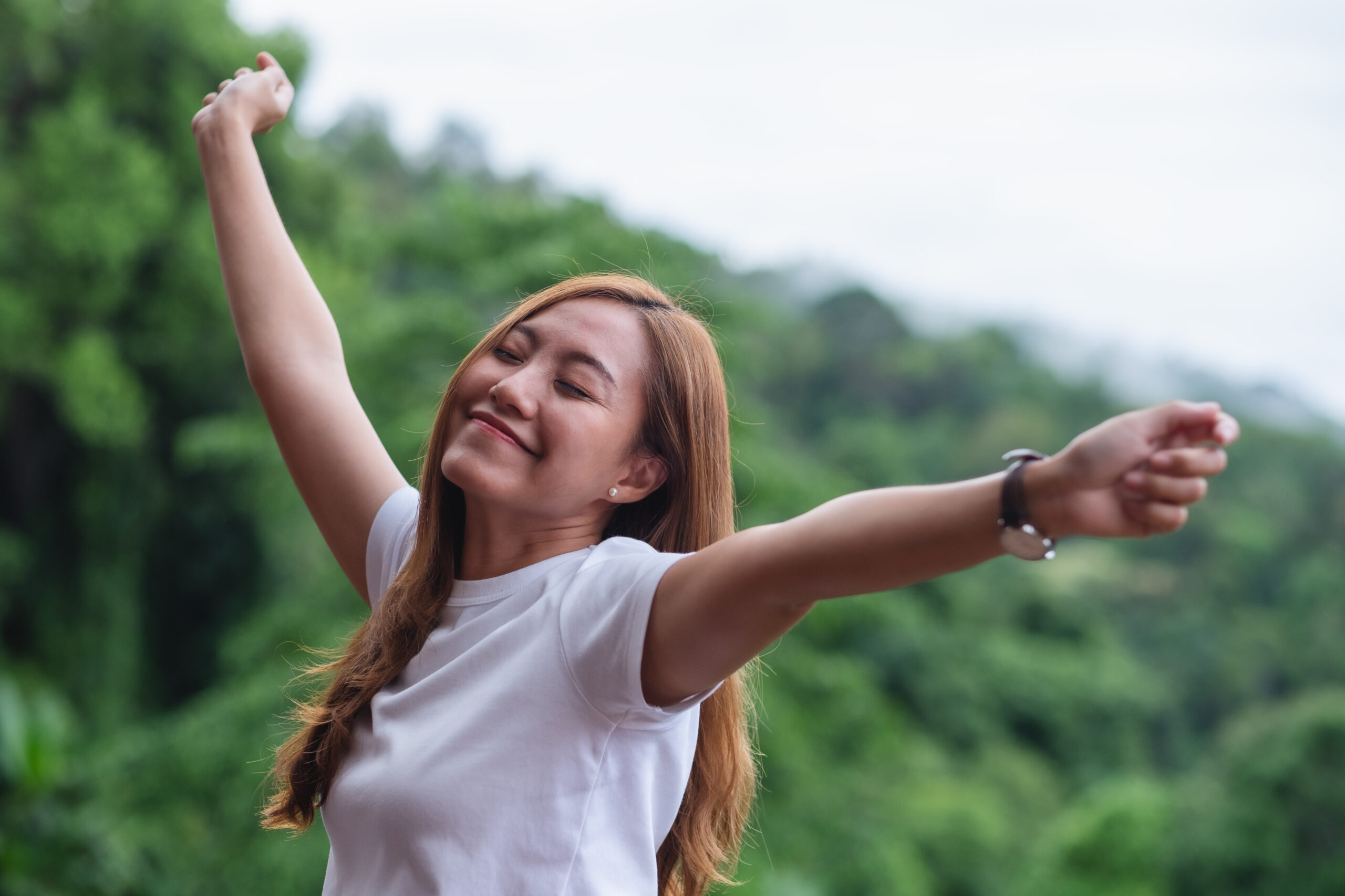 A joyful woman embraces the outdoors with open arms, reflecting the freedom and fulfillment that come from discovering her true calling and living a life of purpose.